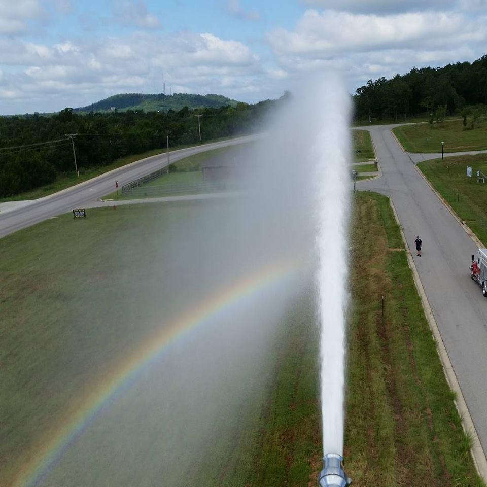 water spraying from fire engine, creating a rainbow in the mist