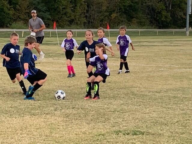 Youth soccer players competing for possession of the ball.