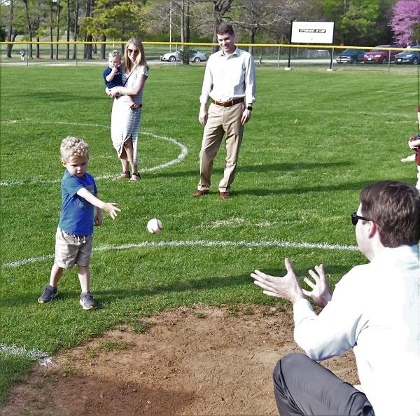 Young child throwing a baseball to a man kneeling on the field