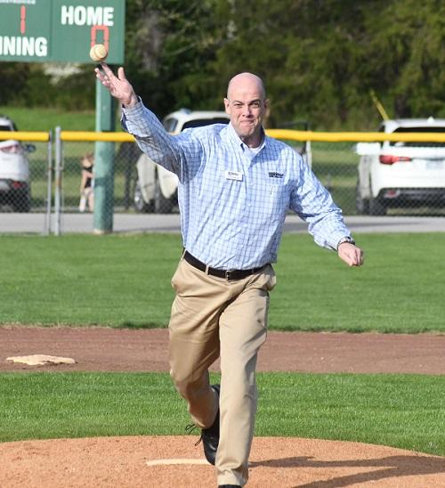 Man in business clothes throwing baseball from pitcher's mound