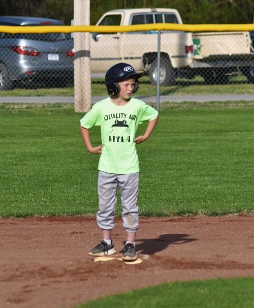 Young boy standing on a base wearing a batting helmet