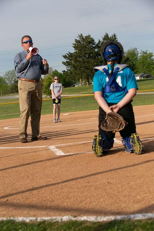 Man with megaphone talking to catcher on the softball field