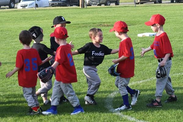 Seven young boys high-fiving each other at the end of the game