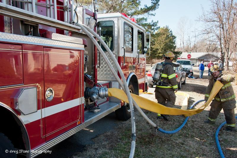 Fire truck and firemen pulling hose