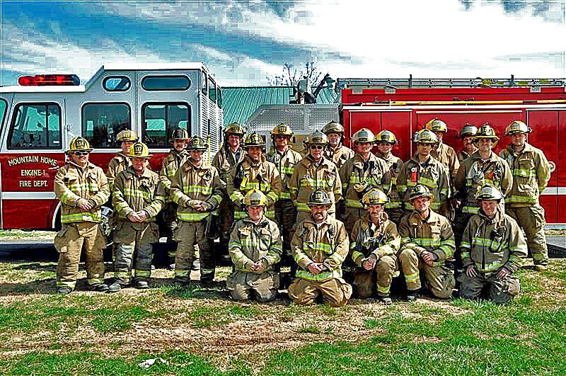 22 fire personnel in uniform standing and kneeling in front of fire truck