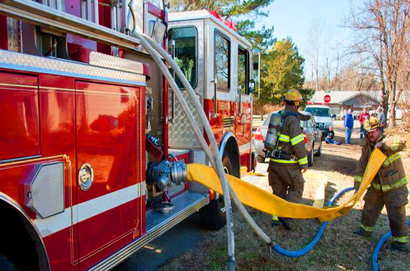 Two fireman pulling hose from firetruck