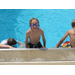 A young boy swimmer with goggles playing in the pool with two friends.