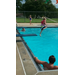A young child wearing a life jacket jumping off the diving board into the pool.
