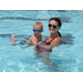 A baby swimming in the pool with a female swimming instructor. 
