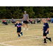 Two youth soccer players making their way down the field.